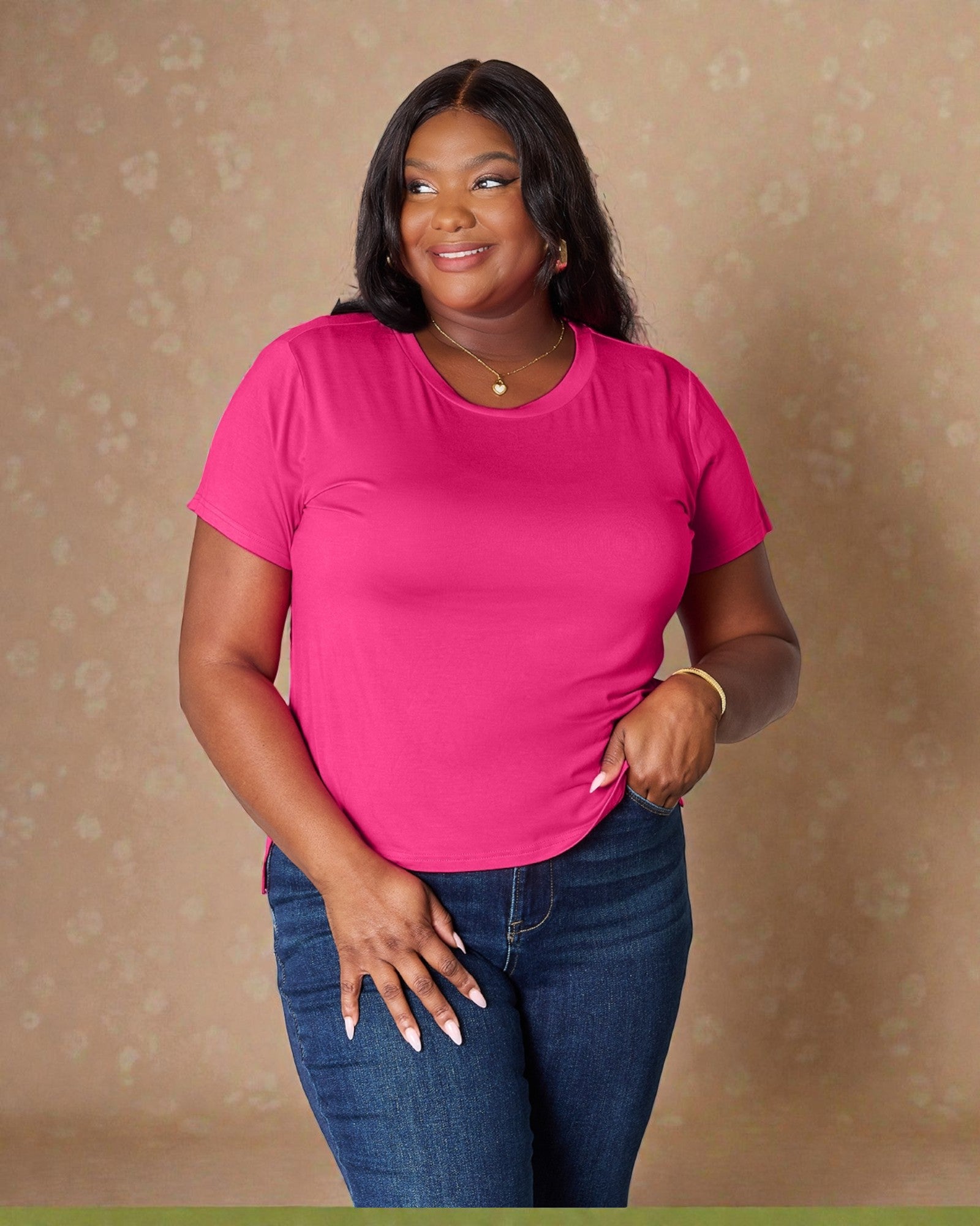 Woman wearing a bright pink t-shirt and blue jeans against a beige background