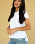 Woman wearing a white t-shirt and blue jeans against a beige background