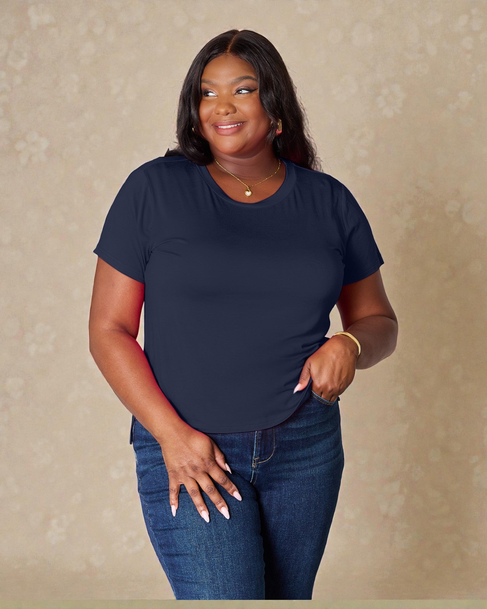 Woman wearing a navy blue t-shirt and jeans against a beige background