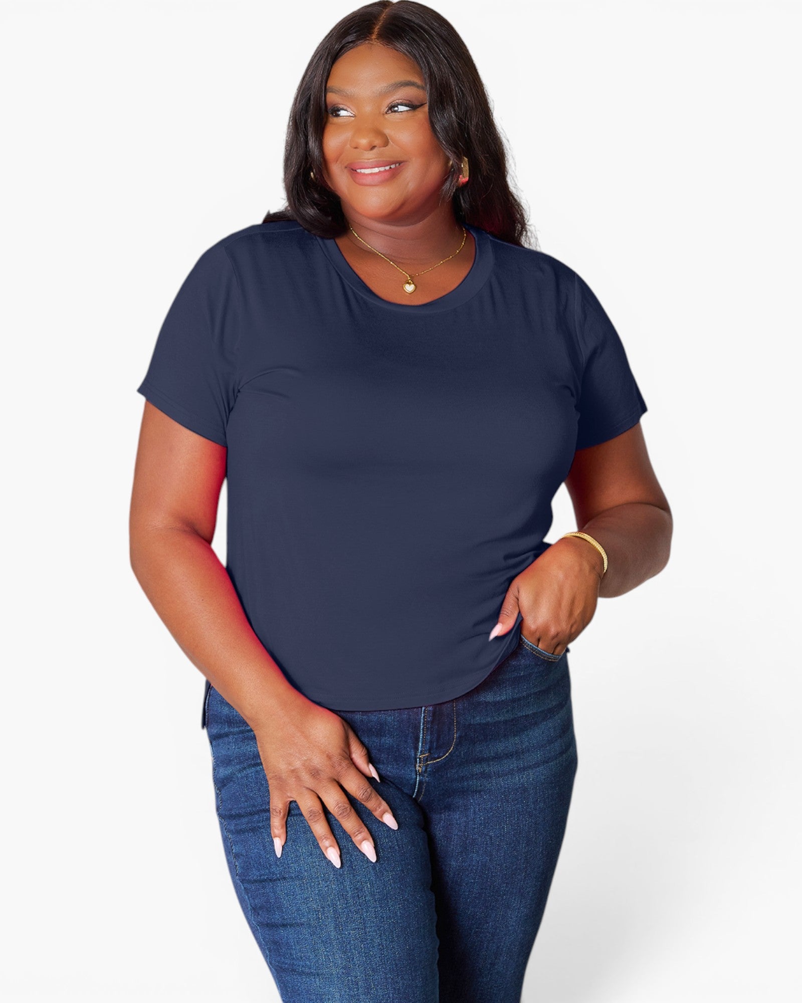 A woman modeling a navy blue short-sleeve crewneck t-shirt with dark blue jeans, standing against a light gray studio background.