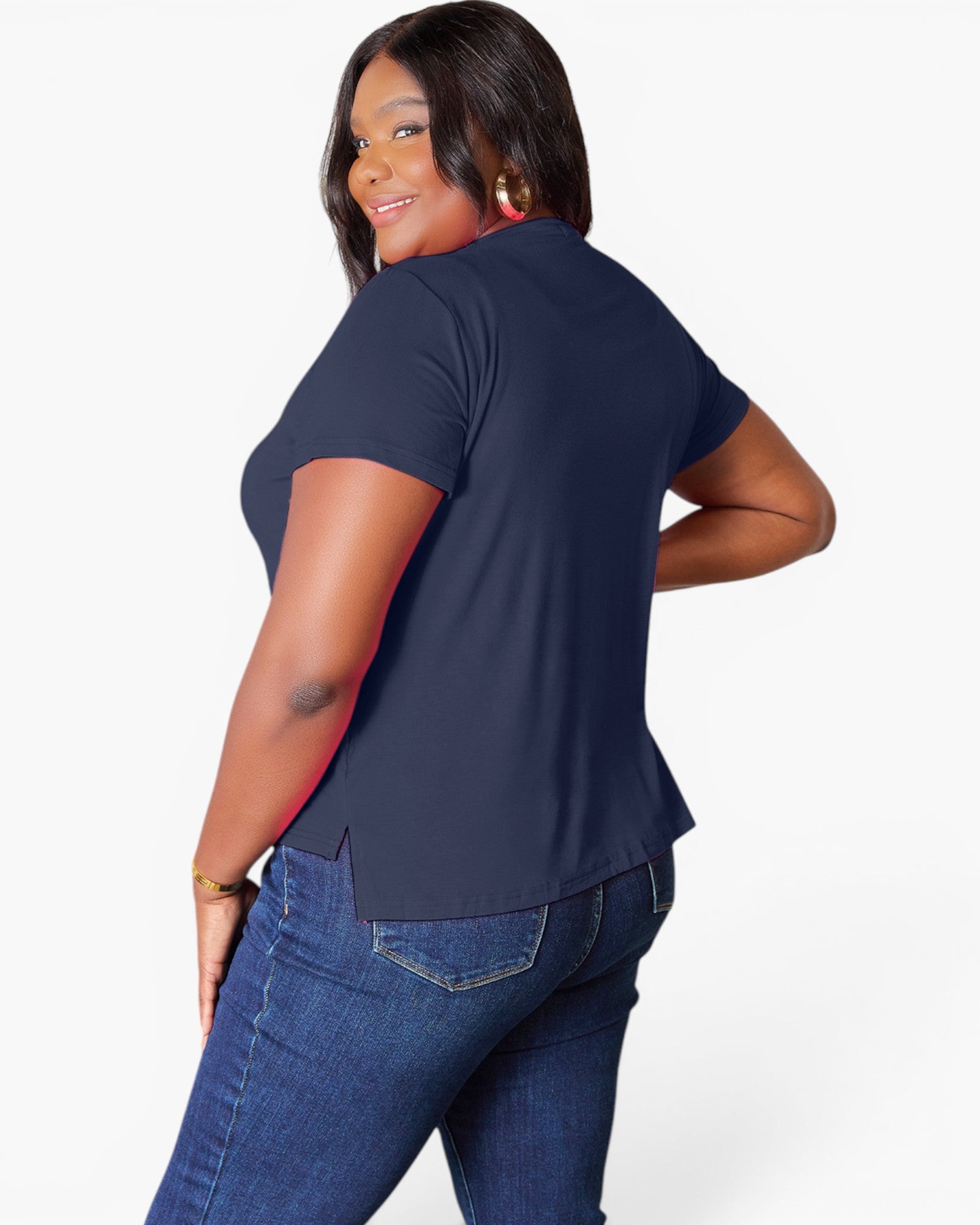 A woman modeling a navy blue short-sleeve t-shirt from the back, paired with blue jeans, against a plain white studio background.