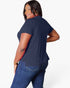 A woman modeling a navy blue short-sleeve t-shirt from the back, paired with blue jeans, against a plain white studio background.