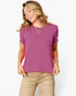 A woman wearing a short-sleeve crewneck t-shirt in a dusty magenta-purple color, paired with beige pants, against a clean white background.