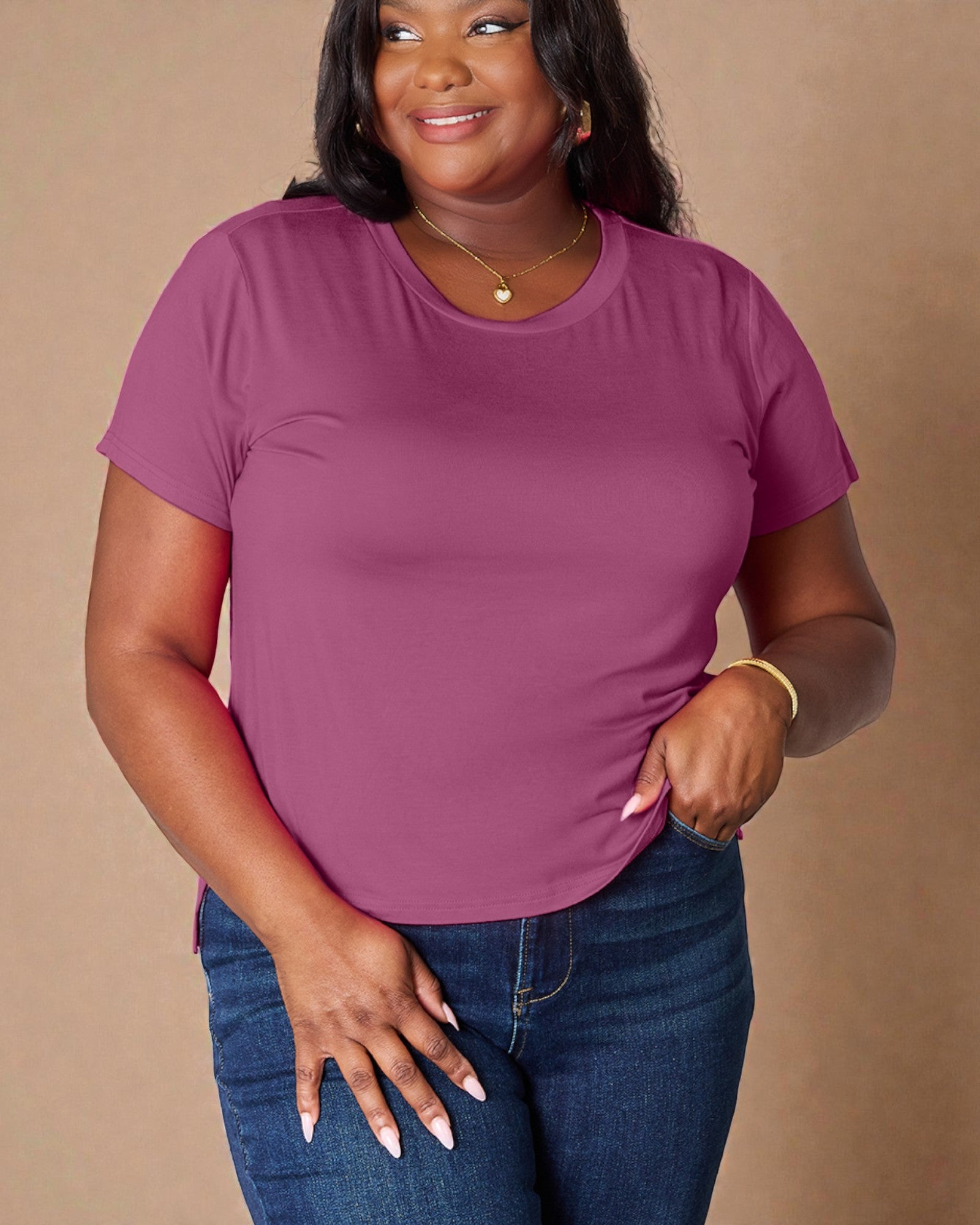 Woman wearing a purple t-shirt and blue jeans against a beige background