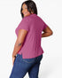 A woman modeling a short-sleeve magenta pink top from the back, paired with blue jeans, against a plain white studio background.