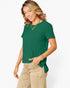 A woman wearing a forest green short-sleeve top with a side tie detail and beige cargo pants, photographed against a clean white studio background.