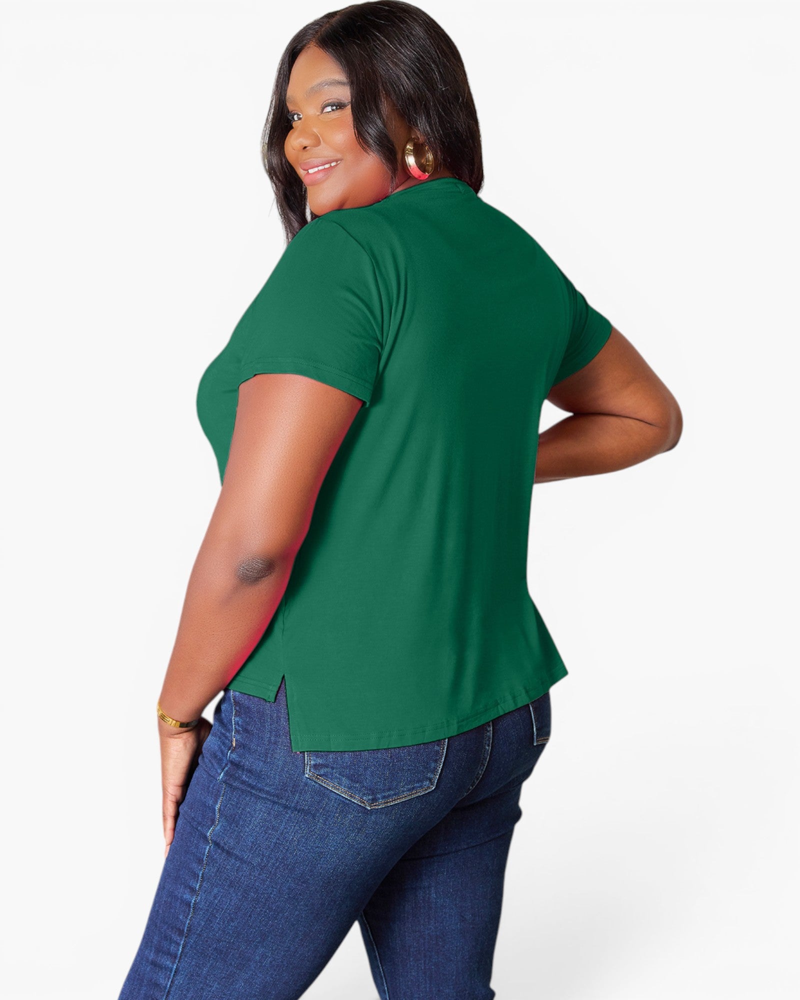 A woman modeling a green short-sleeve top from the back, paired with blue jeans, against a plain white studio background.