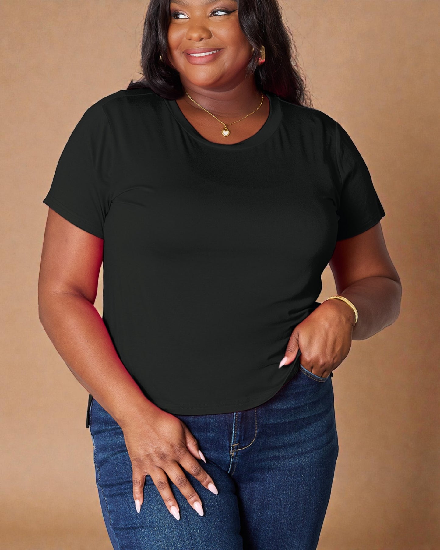 Woman wearing a black t-shirt and blue jeans against a beige background