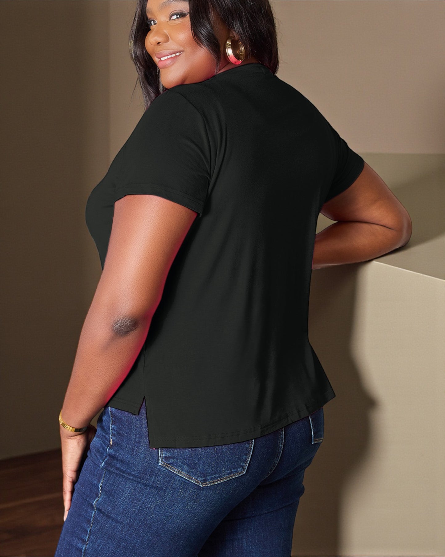 Person wearing a black t-shirt and blue jeans against a neutral background