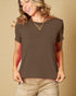 Woman wearing a brown t-shirt and beige pants against a beige background