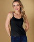 Woman wearing a black tank top and blue jeans against a beige background