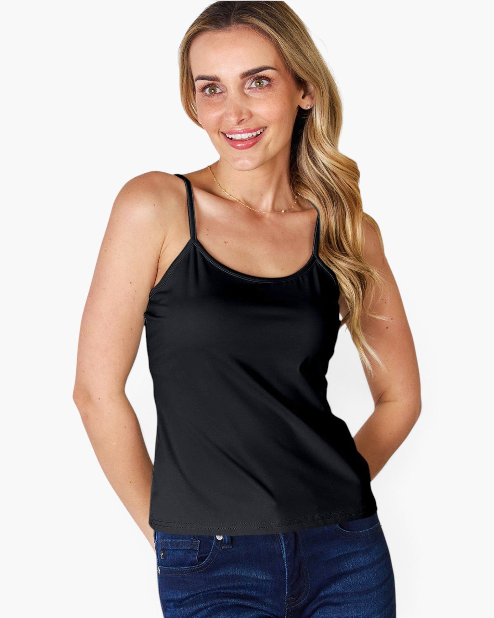 A woman wearing a black spaghetti-strap camisole tank top and blue jeans, posing against a solid white background.