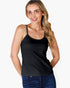 A woman wearing a black spaghetti-strap camisole tank top and blue jeans, posing against a solid white background.