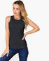 A woman modeling a sleeveless black crewneck tank top paired with blue jeans, set against a plain white studio background.