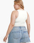 A woman shown from the back wearing a fitted white sleeveless crop top and light blue denim shorts against a plain light gray studio background.