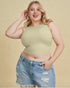 Woman wearing a green crop top and denim shorts on a beige background