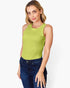 A woman wearing a sleeveless lime green tank top and dark blue jeans, standing against a light gray studio background.