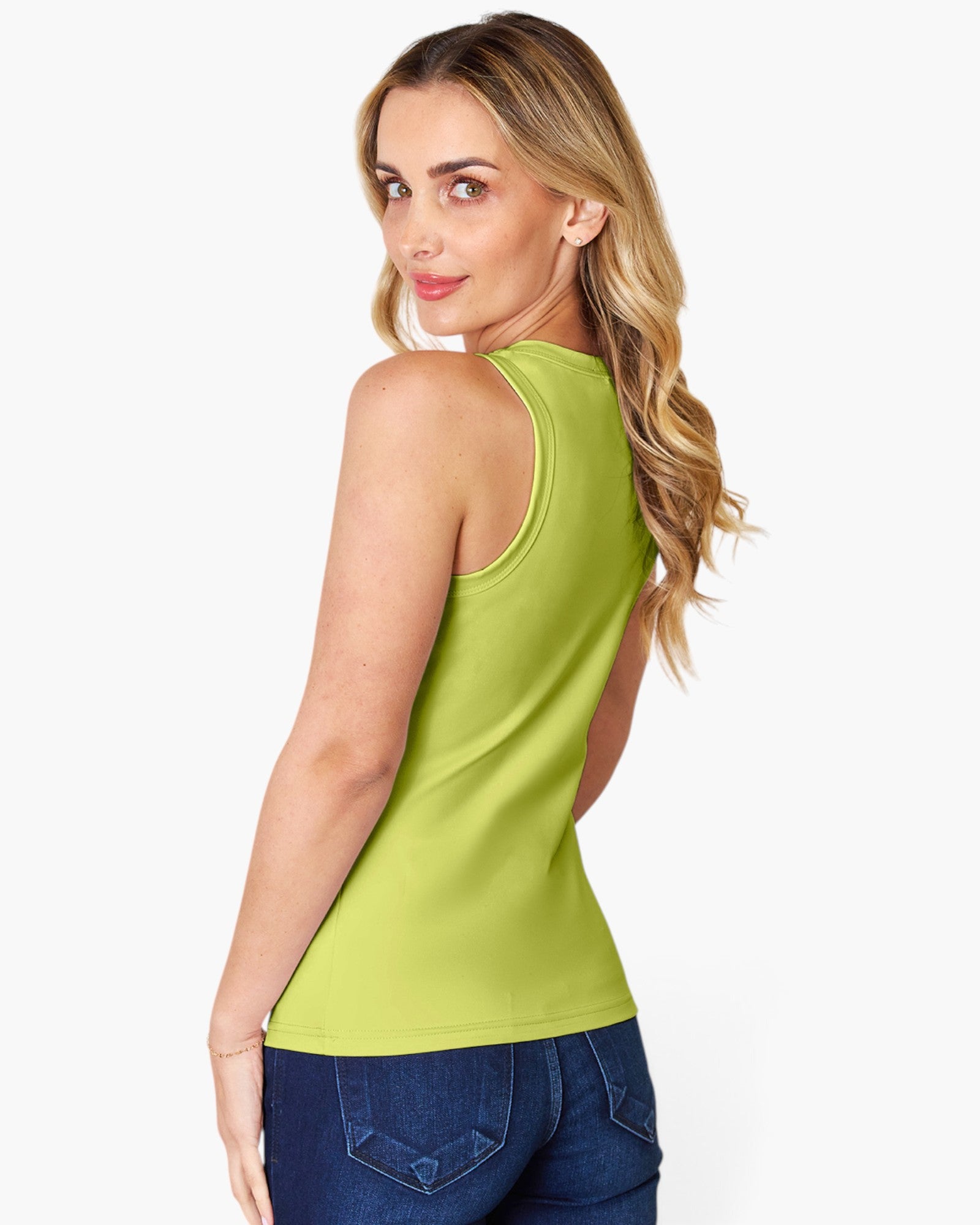 A woman wearing a bright lime green sleeveless tank top and blue jeans, shown from a three-quarters back view against a light gray studio background.