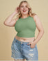 Woman wearing a green crop top and denim shorts against a beige background