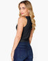A woman wearing a black sleeveless tank top and dark blue jeans, photographed from the back against a light gray studio background.