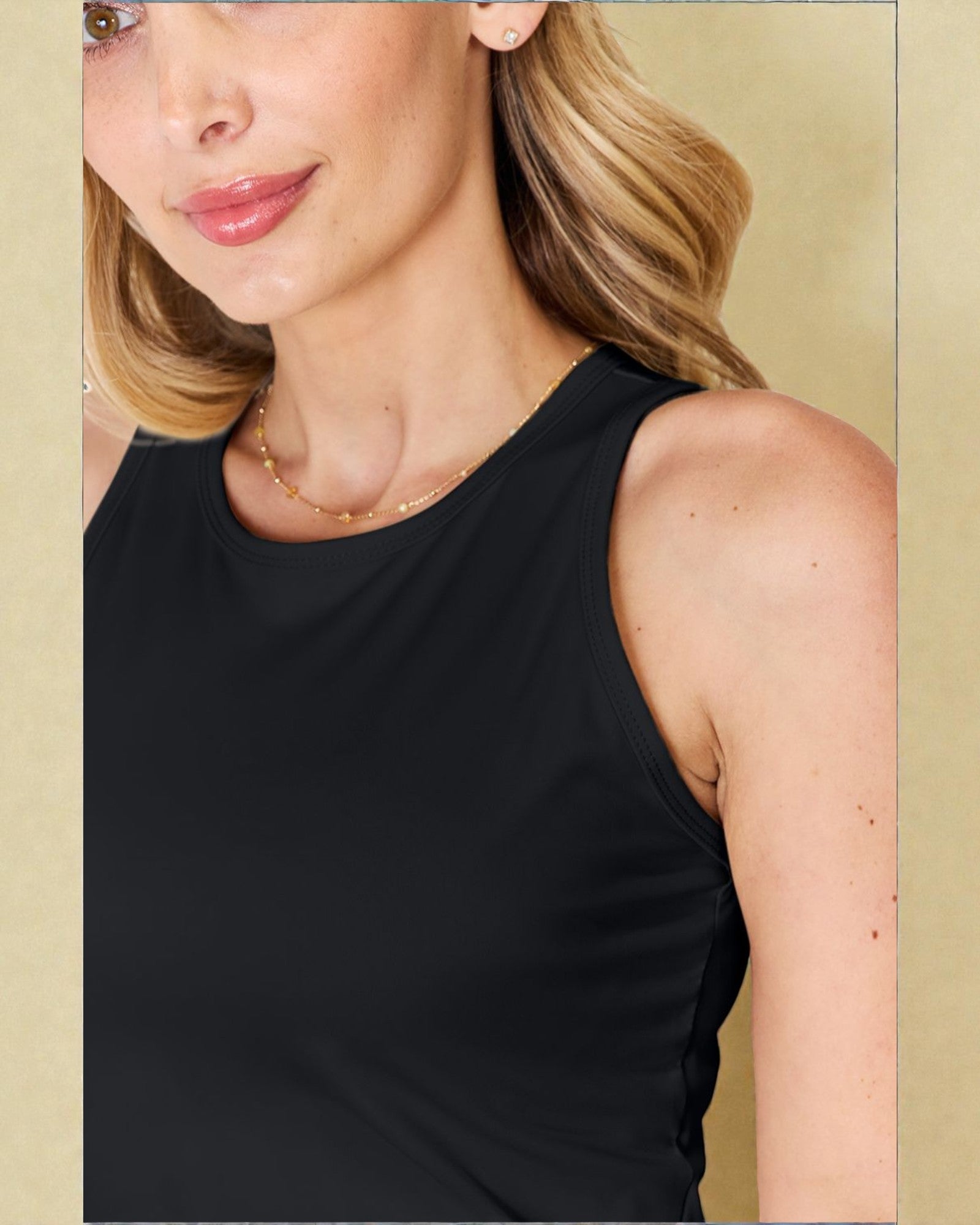 Woman wearing a black sleeveless top with a beige background