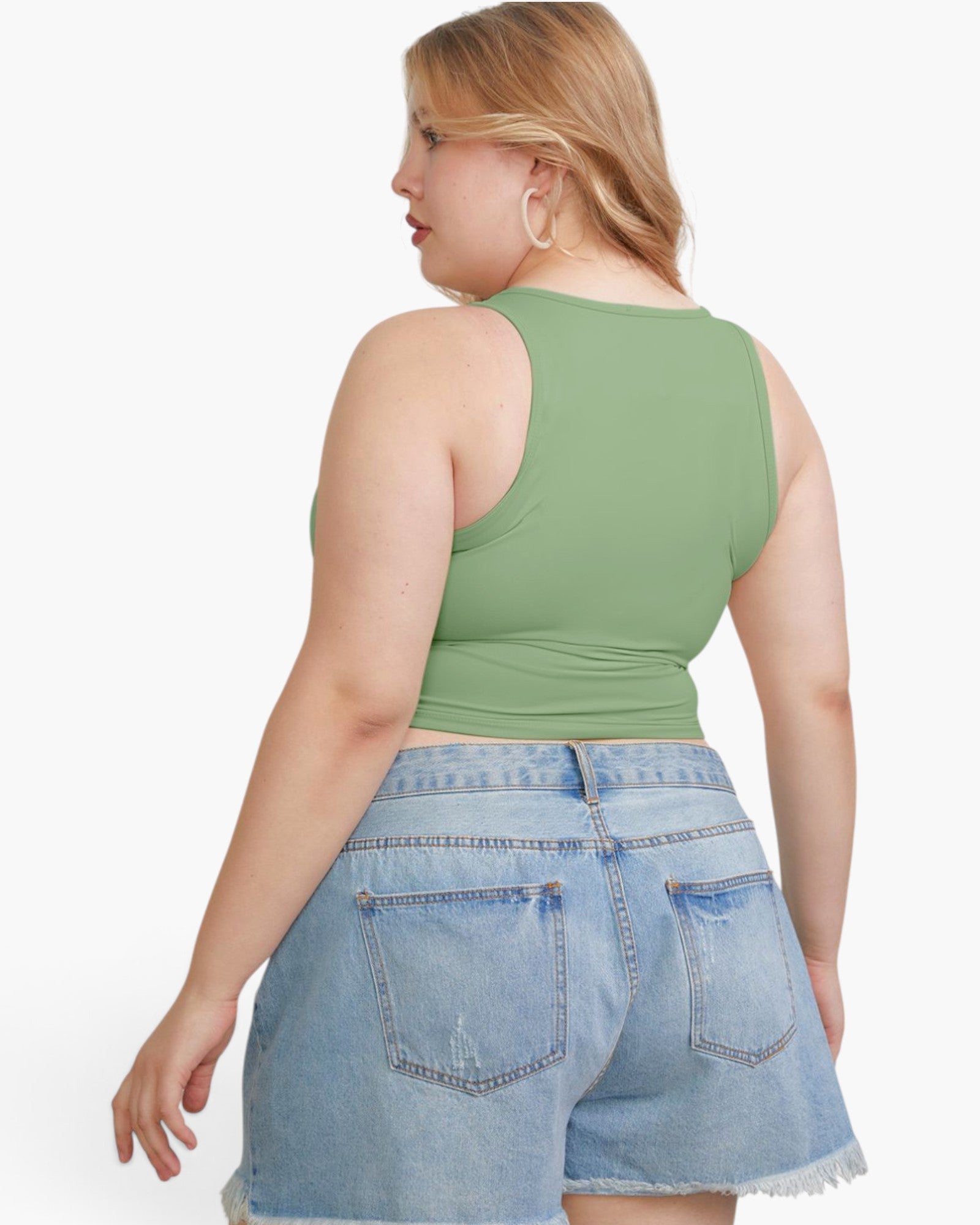 A woman shown from the back wearing a sage green sleeveless crop top and light blue denim shorts against a plain white background.