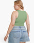 A woman shown from the back wearing a sage green sleeveless crop top and light blue denim shorts against a plain white background.