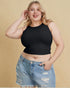 Woman wearing a black crop top and denim shorts against a beige background