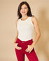 Woman wearing a white sleeveless top and red pants against a beige background