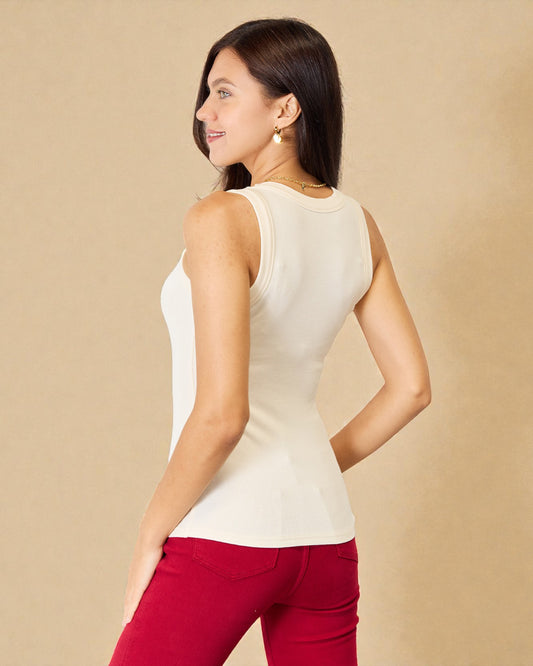 Woman wearing a white sleeveless top and red pants on a beige background