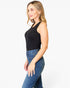 A woman modeling a black sleeveless scoop-neck tank top paired with blue jeans, shown from a side profile against a plain white studio background.