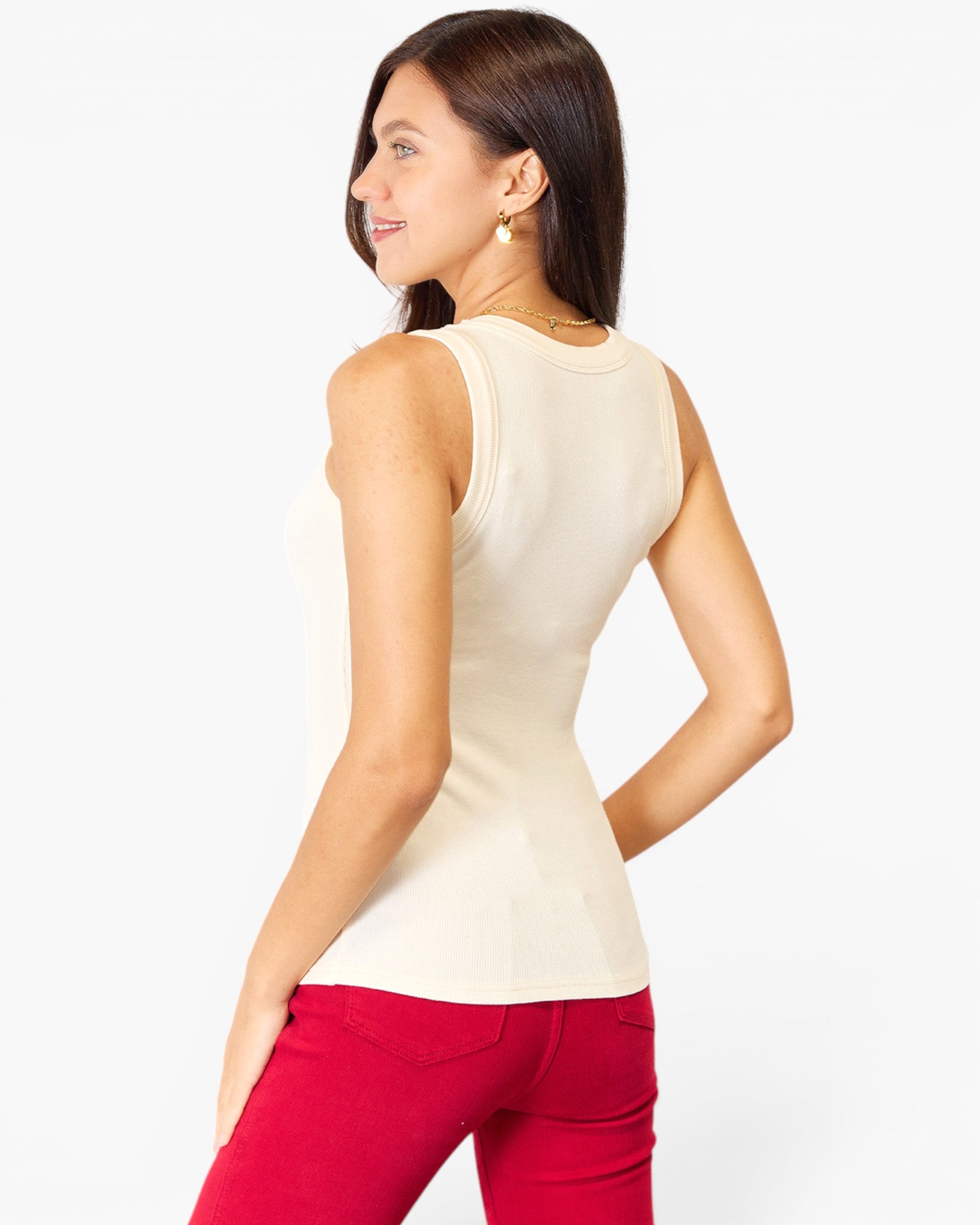 A woman shown from the back wearing a fitted sleeveless cream top and bright red pants against a clean white studio background.