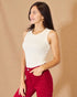Woman wearing a white sleeveless top and red pants against a beige background