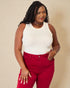 Woman wearing a white sleeveless top and red pants against a beige background
