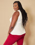 Woman wearing a white sleeveless top and red pants against a beige background