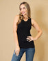 Woman wearing a black tank top and blue jeans against a beige background