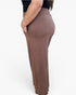 A side view of a person wearing a pair of high-waisted, wide-leg knit pants in a muted taupe-brown color, with a black top partially visible.