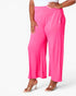 Bright pink wide-leg cropped pants worn by a model, paired with a white top and clear high-heel sandals, against a clean white studio background.