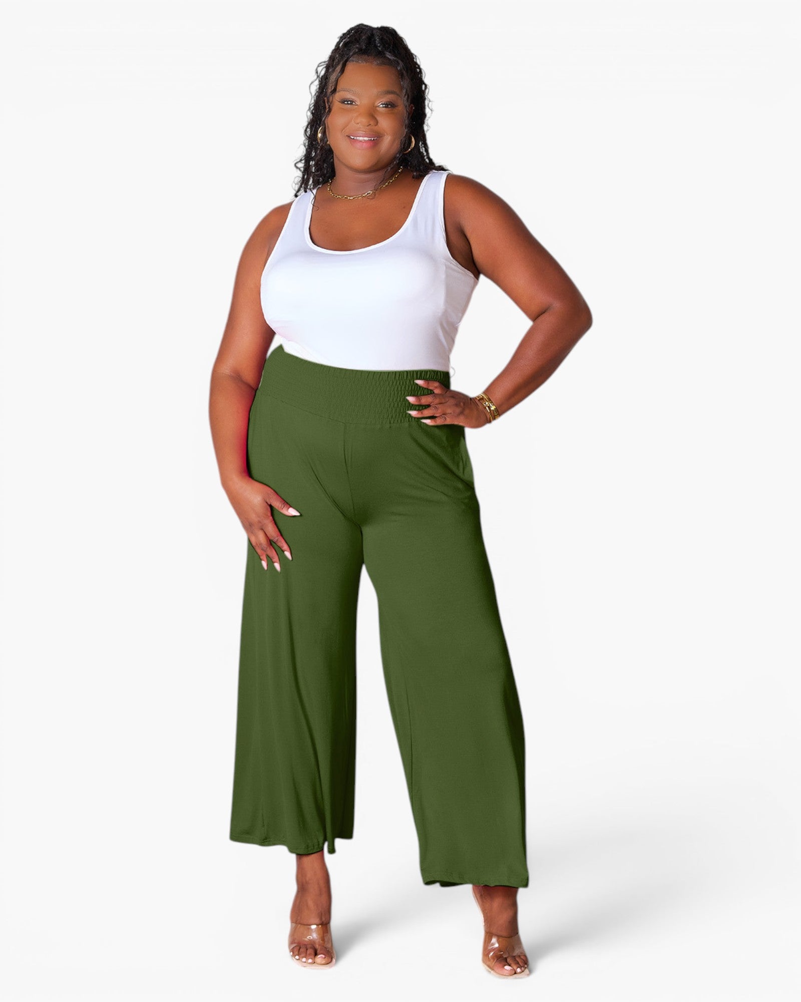 A woman modeling a pair of olive green wide-leg cropped pants with a white tank top, standing against a plain white studio background.