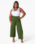A woman modeling a pair of olive green wide-leg cropped pants with a white tank top, standing against a plain white studio background.