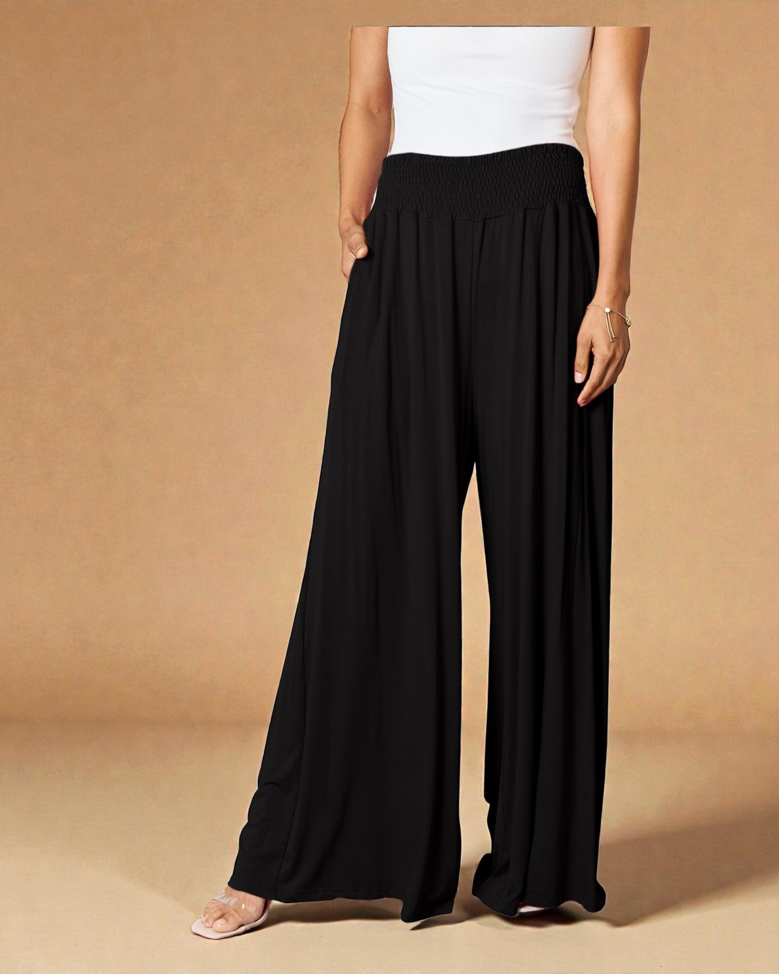 Person wearing black wide-leg pants and a white top on a beige background