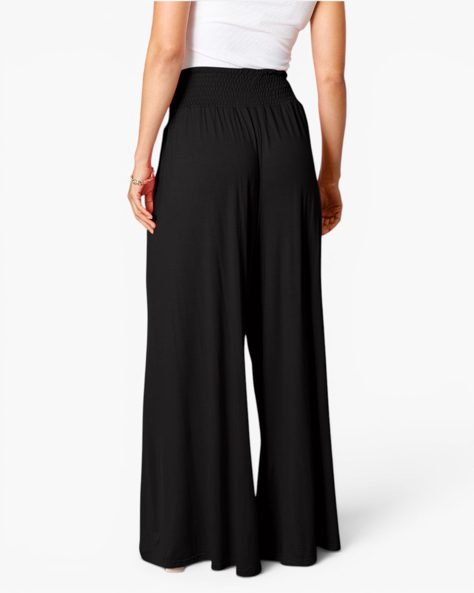 A model from the back wearing black wide-leg pants with an elastic waistband, paired with a white top, against a clean white studio background.