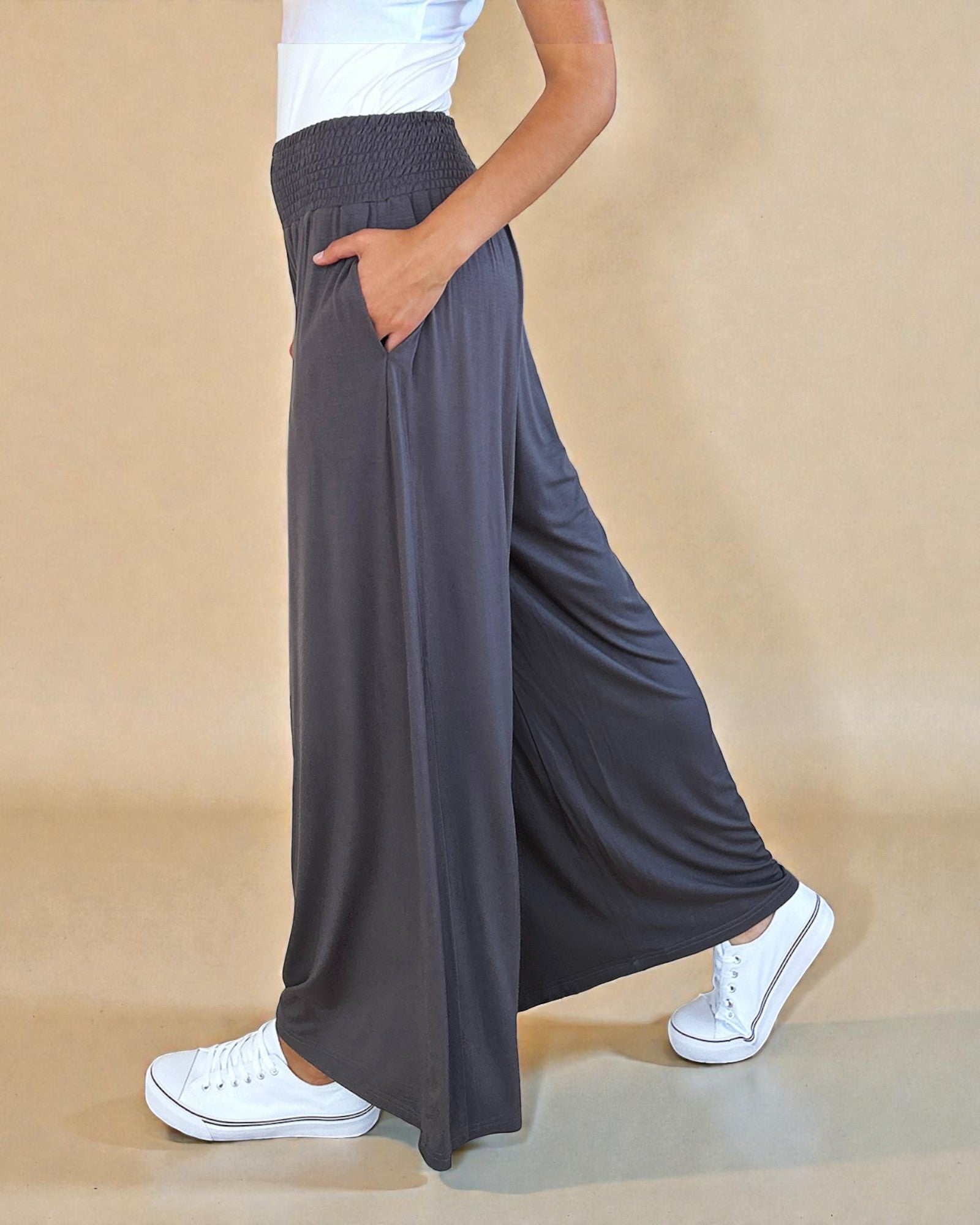 Person wearing dark gray wide-leg pants with a beige background