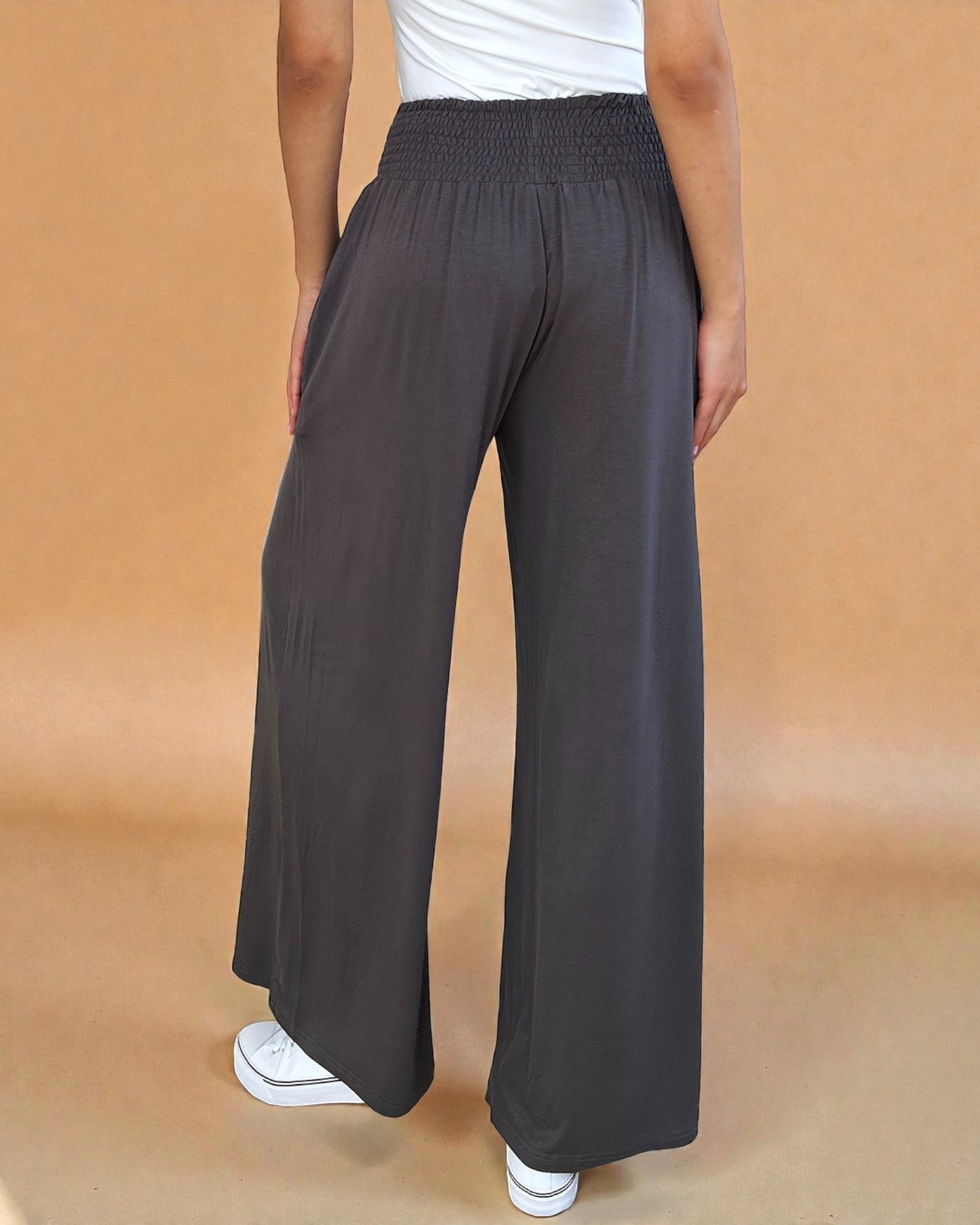 Person wearing dark gray wide-leg pants on a beige background