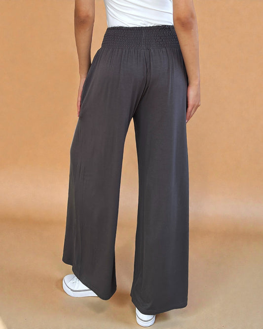 Person wearing dark gray wide-leg pants on a beige background