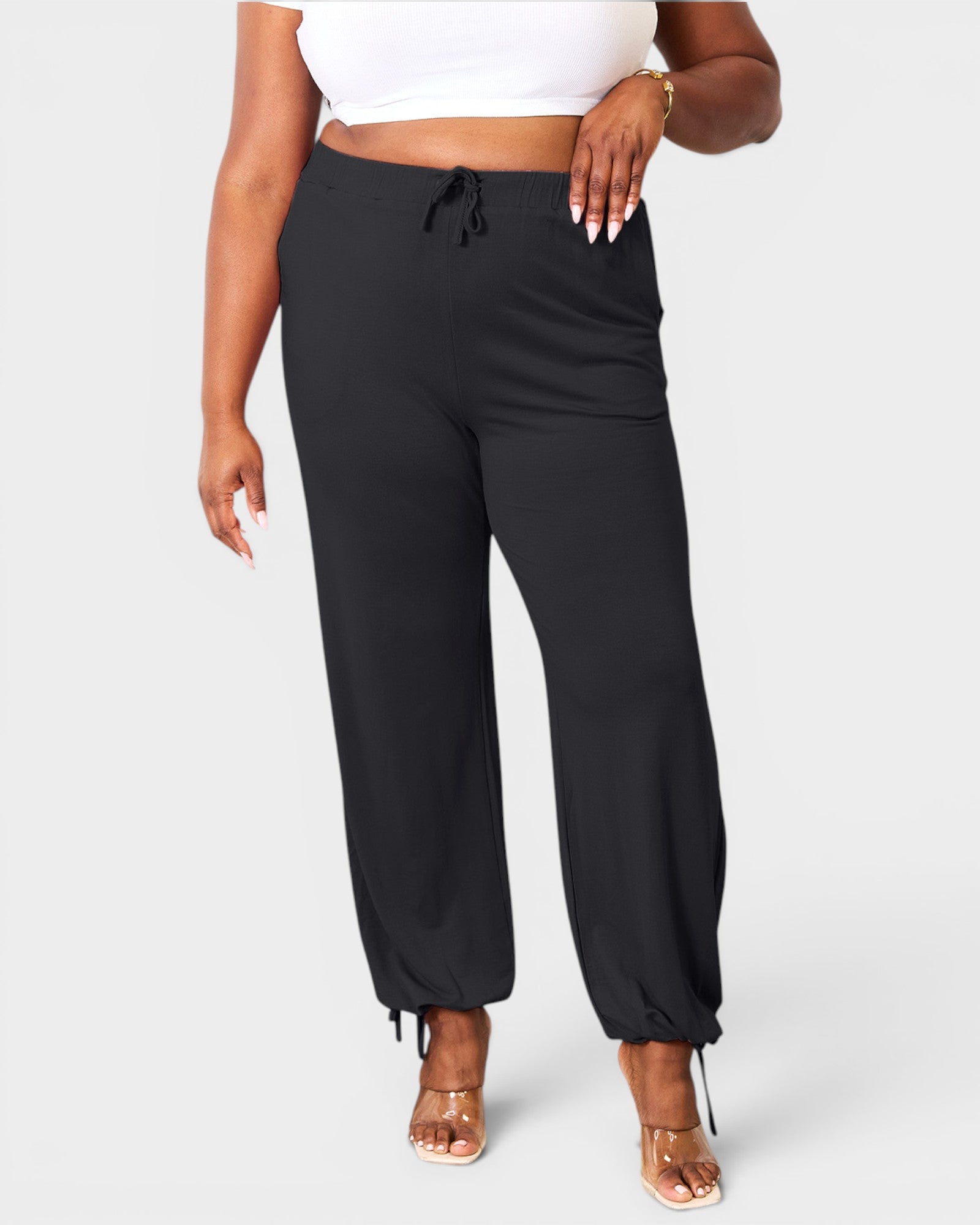 Person wearing black jogger pants on a white background