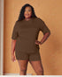 Woman wearing a brown outfit against an orange wall