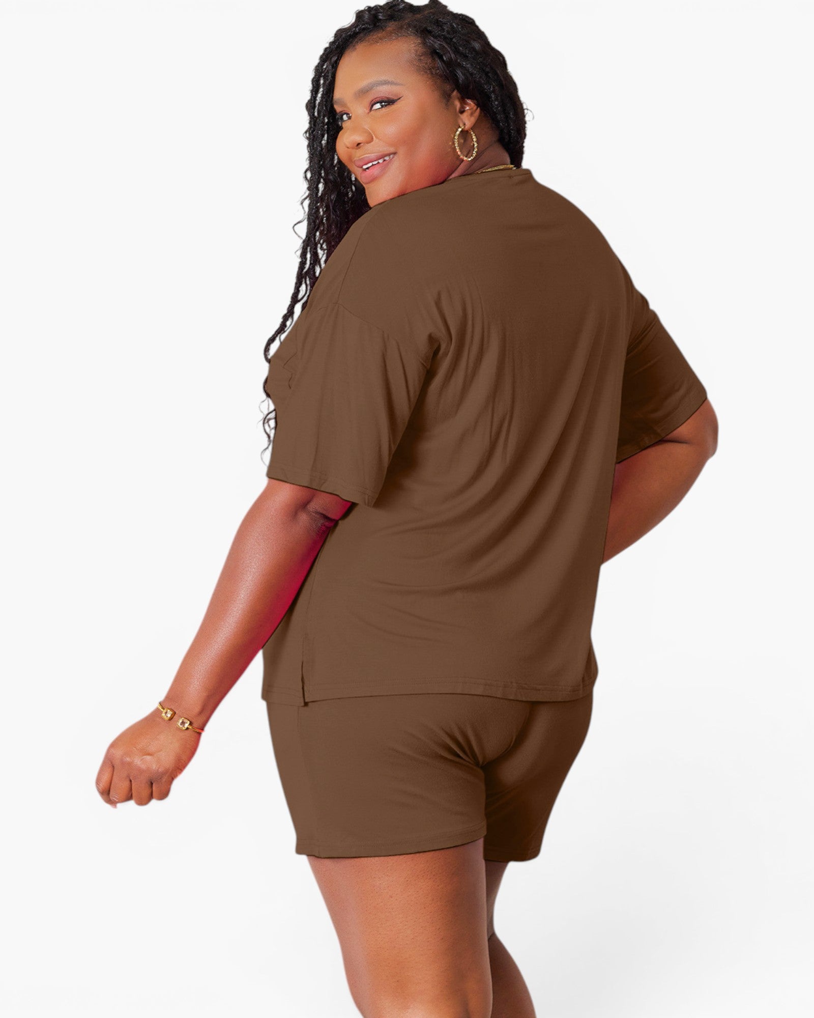 A woman modeling a matching brown short-sleeve t-shirt and shorts set, shown from a three-quarters back view against a plain white studio background.