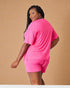 Woman wearing a bright pink outfit against a beige background