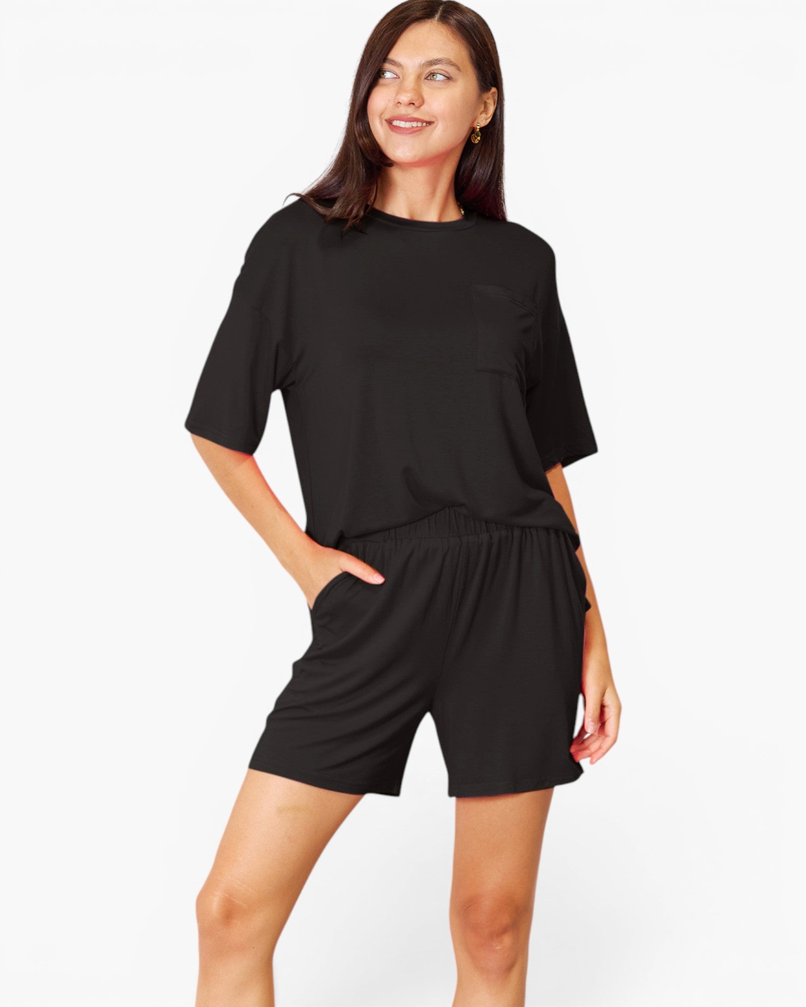 A woman modeling a black short-sleeve lounge set consisting of a crewneck top and matching shorts, photographed against a clean white studio background.